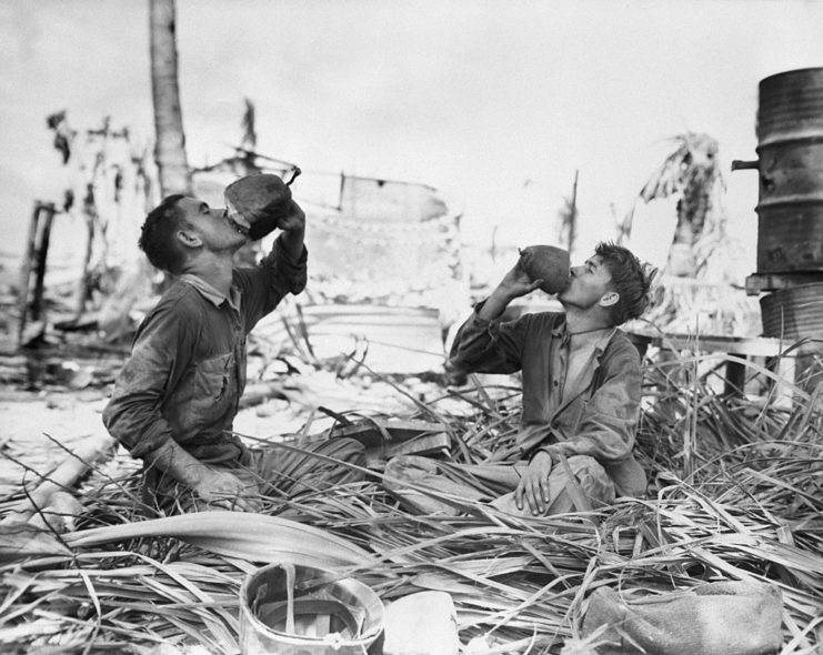 Matos J.R. Griffen and E.E. Reynolds drinking coconut milk while sitting in tall grass