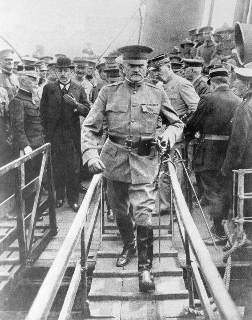 John J. Pershing walking off a ship while a large crowd of men stand behind him