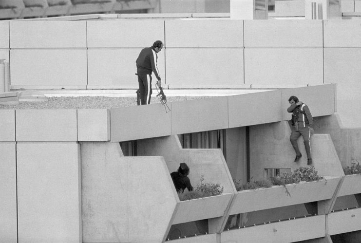 Three police officers jumping onto an apartment terrace from the building's roof
