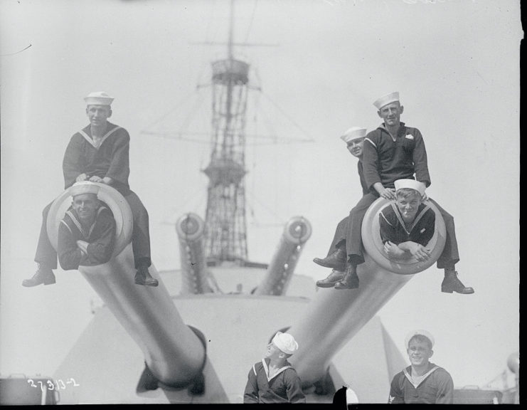 US Navy sailors sitting atop the guns of the USS Texas