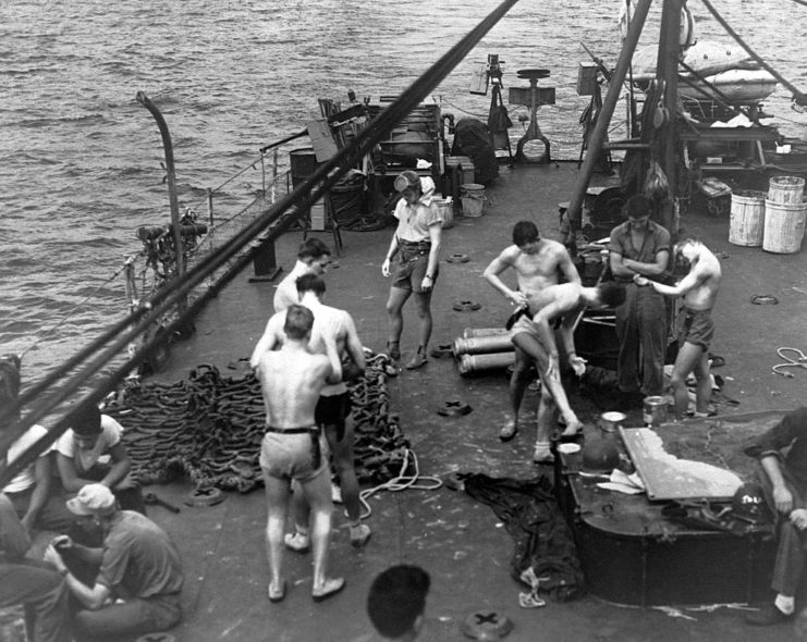 Frogmen painting their bodies in camouflage while dressed in swim trunks