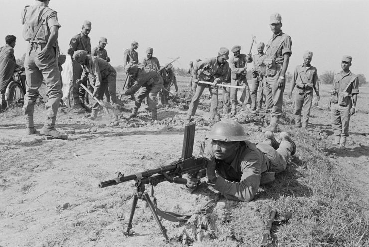 Soldier aiming a Bren light machine gun with others watch