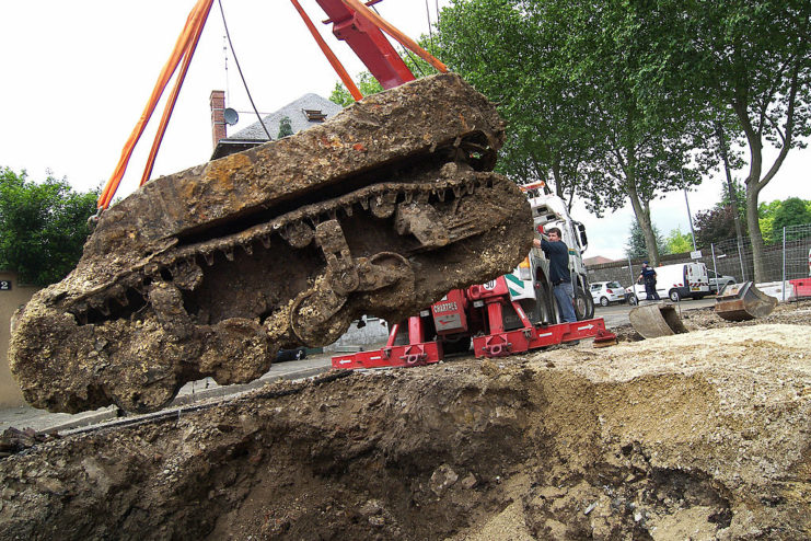 Crew raising a mud-covered M5 Stuart Light Tank from the ground with a machine