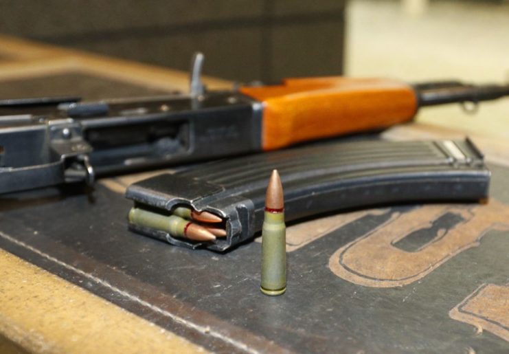 7.62 x 39 mm round sitting beside an AK-47 and a .30-round magazine