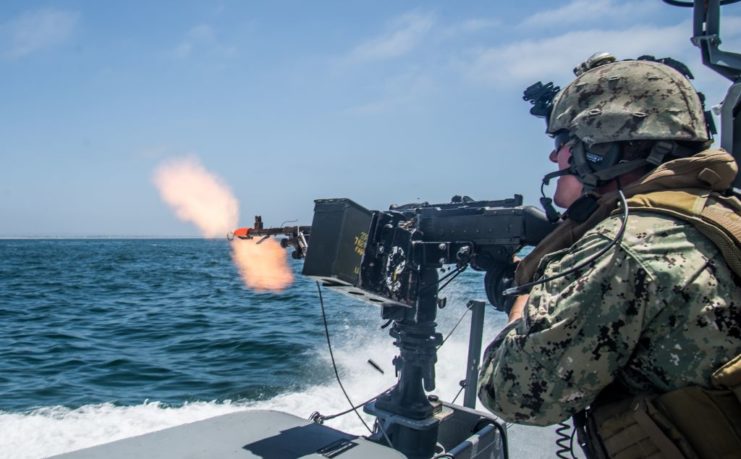 US military service member firing an M240 while at sea