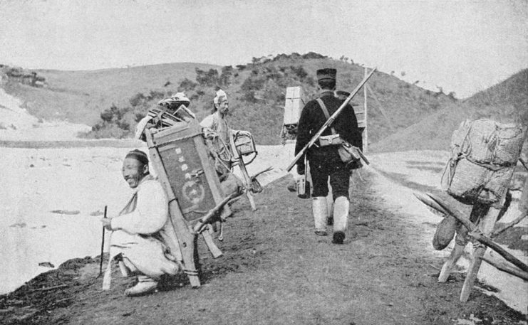 Japanese soldier walking by Korean forced laborers