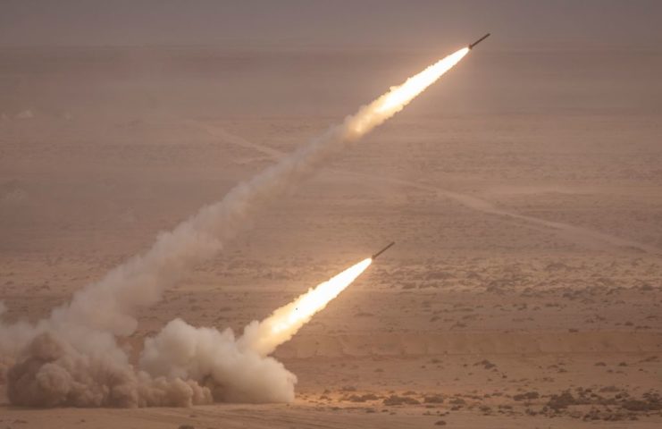 Two artillery rockets being fired in the desert