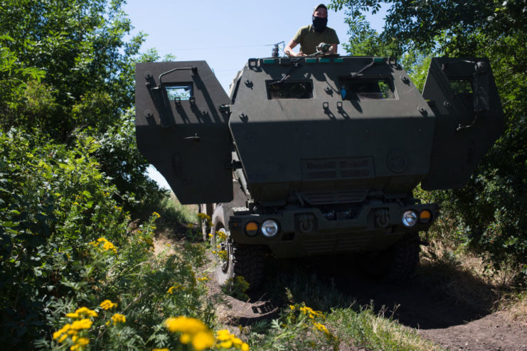 Ukrainian serviceman sitting on top of an M142 HIMARS