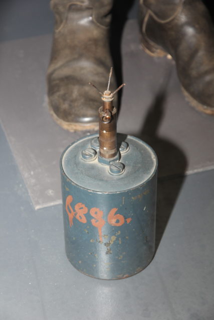 Person standing beside an S-Mine 35 placed on the ground