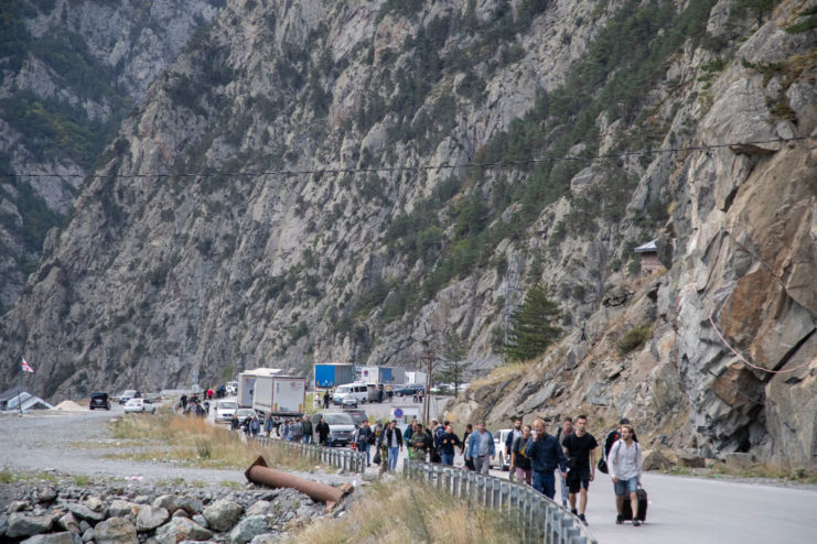 Citizens fleeing Russia's mobilization efforts walking along a mountainside road