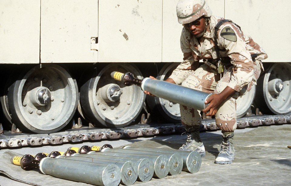 Soldier placing a sabot round on the ground, beside a number of others