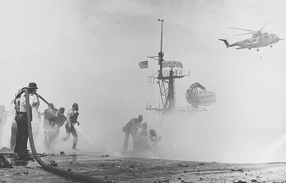 Firefighters trying to stop a fire on the deck of the USS Forrestal (CV-59)