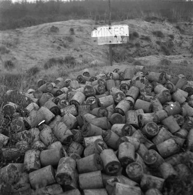 Pile of discarded S-mines sitting in front of a sign that reads "MINES"