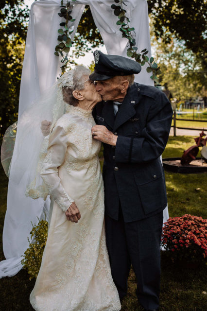 Frankie and Royce King kissing beneath a veiled arch