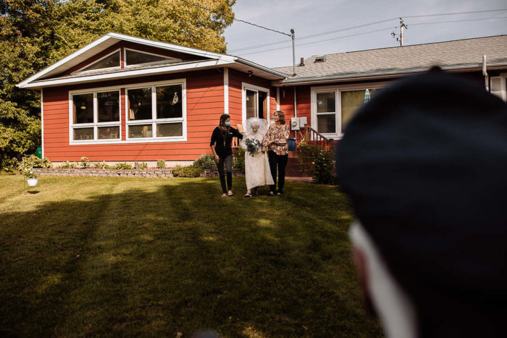 Frankie King walking across a lawn in her wedding dress, with her daughter and another woman walking alongside her