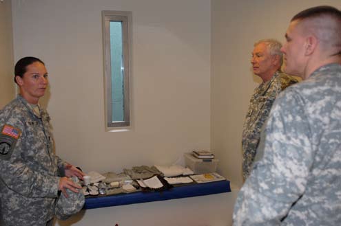 Three US military officials standing inside a solitary confinement cell at Guantanamo Bay detention camp