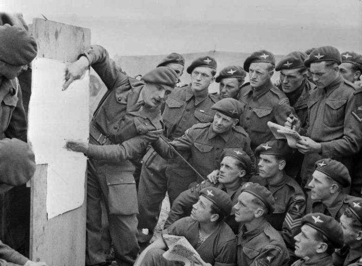 Men with the 22nd Independent Parachute Company, 6th Airborne Division watching their commander go over the plans for Operation Tonga