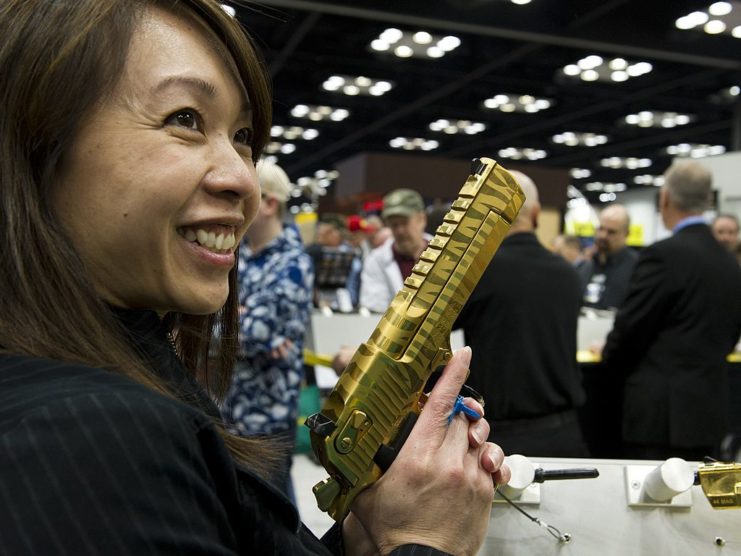 Woman holding up a gold-plated Desert Eagle