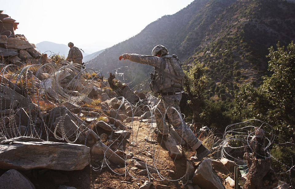 US Army soldiers walking along a dirt path in the Korengal Valley
