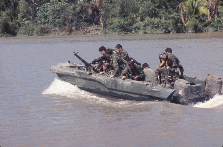 Members of US Navy SEAL Team One riding in an assault boat down the Bassac River