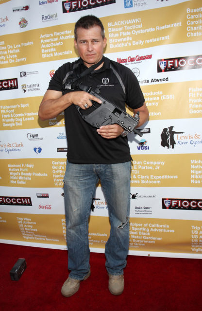 Tim Abell holding a prop gun on a red carpet