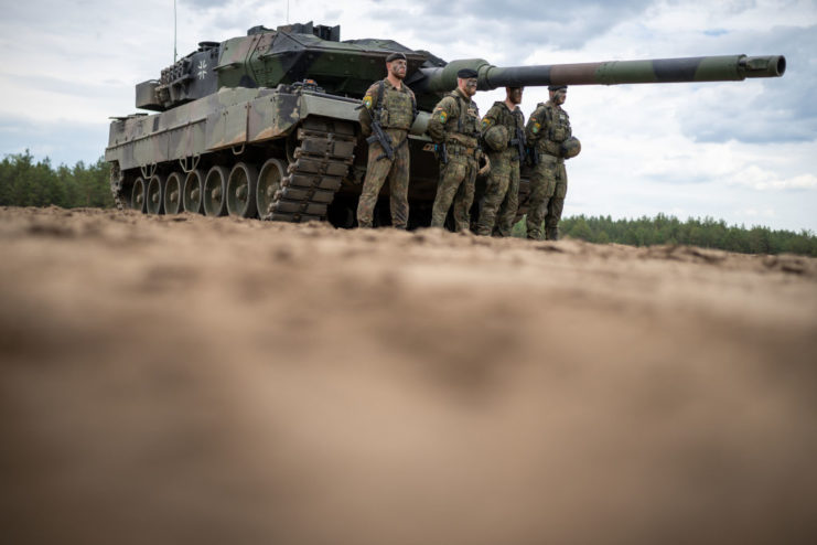 Four soldiers standing in front of a Leopard 2