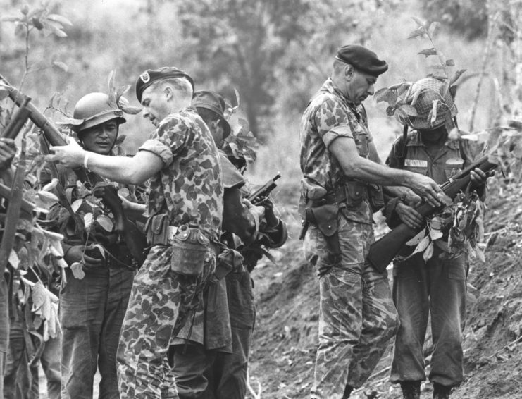Two US Special Forces soldiers instructing South Vietnamese troops on how to accurately fire their weapons