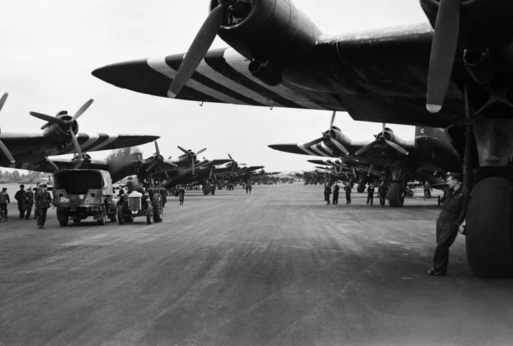 Royal Air Force (RAF) airmen standing around grounded Short Stirling Mark IVs on a runway