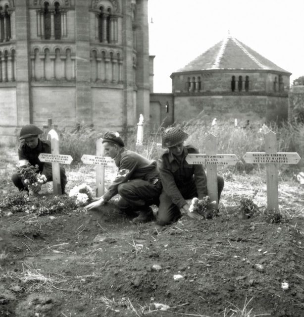 Three Canadian soldiers laying flowers on four civilian graves