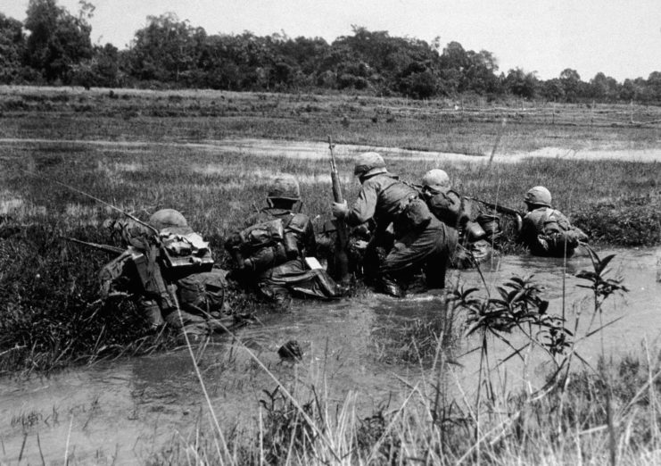 Five US soldiers crouched in a creek