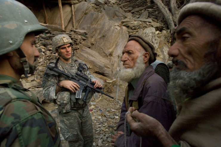 Two US Army soldiers speaking with two Afghani elders