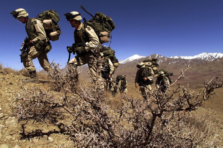 US Army soldiers climbing a rugged hillside