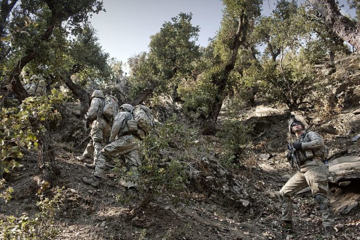 US Army soldiers climbing a rugged hill in the Korengal Valley