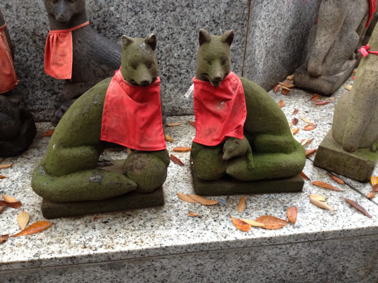 Two fox statues with red bandanas around their necks