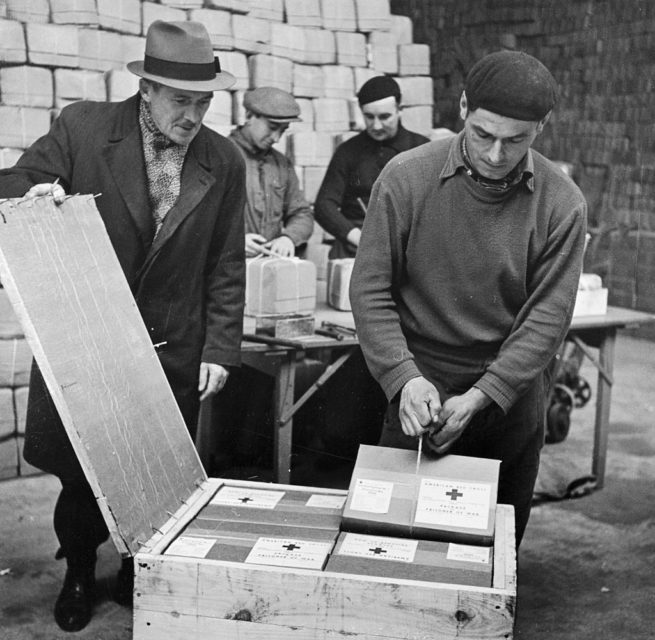 Red Cross workers taking packages out of a wooden crate