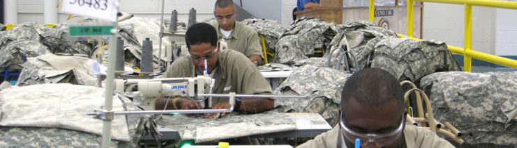 Prisoners sewing together military uniforms at tables