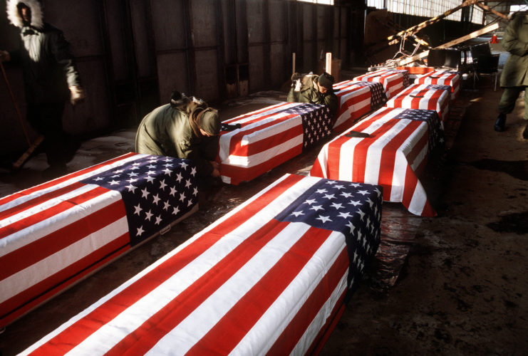 Soldiers attaching American flags to coffins