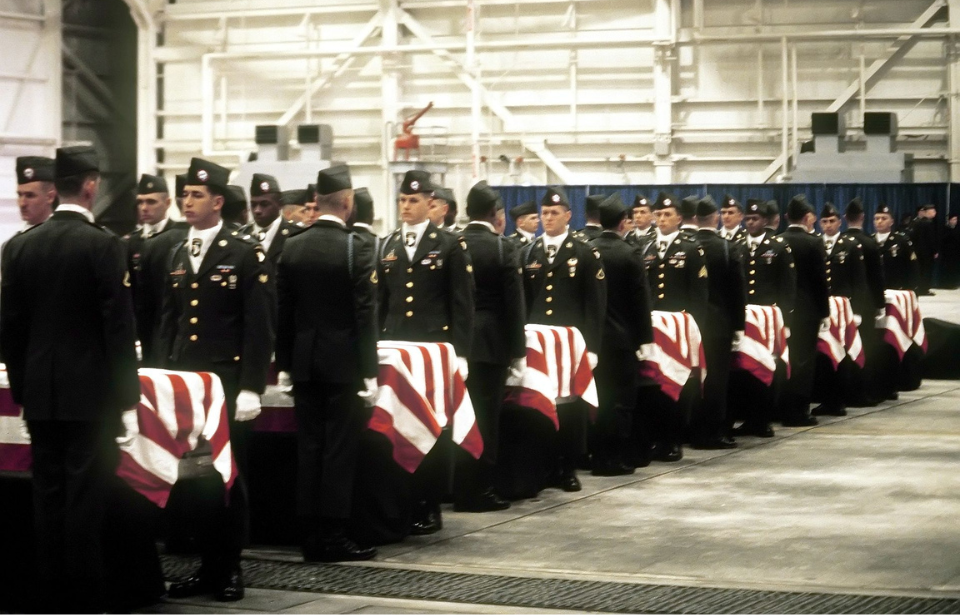 Members of the 101st Airborne standing before caskets draped in American flags