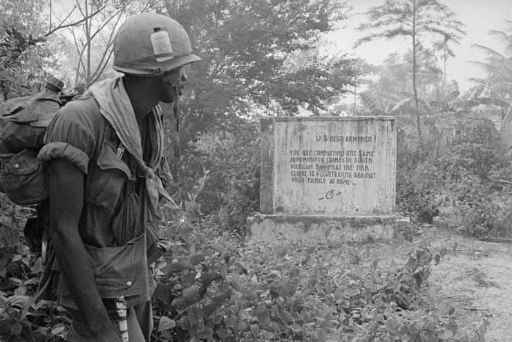 Soldier walking past a gravestone in the Vietnam jungle