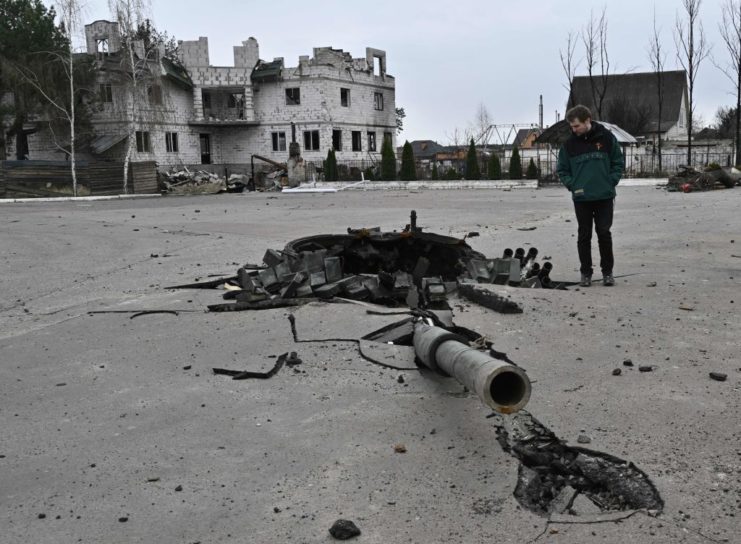 Man standing beside the main gun of a damaged Russian tank