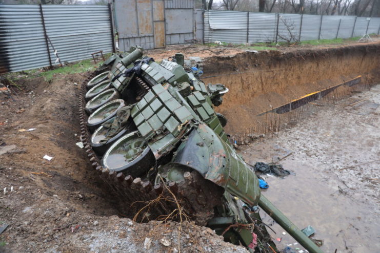Damaged Russian tank half-collapsed in a large hole