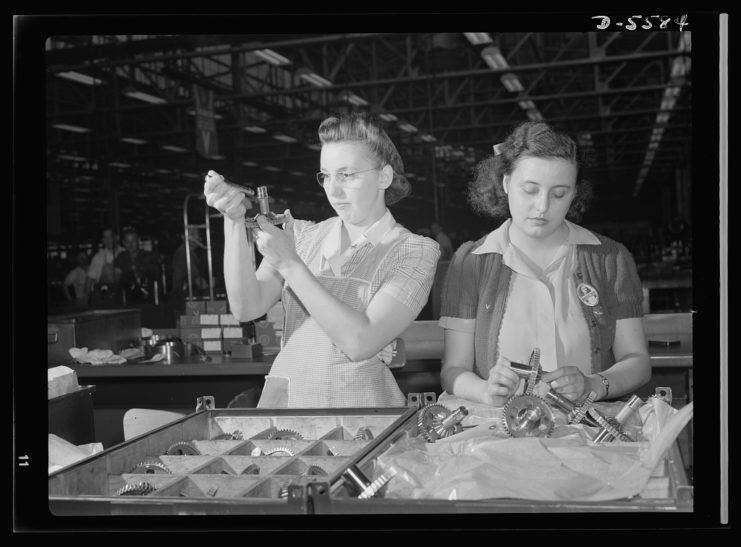 Dorothy Miller and Sylvia Dreiser handling metal gears as they come down the assembly line