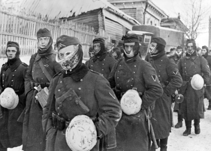 German soldiers marching together down a street in Russia