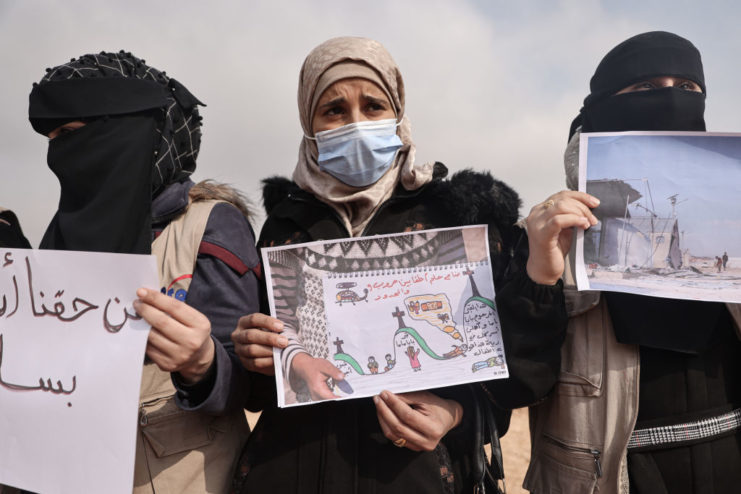 Three female activists holding up protest signs