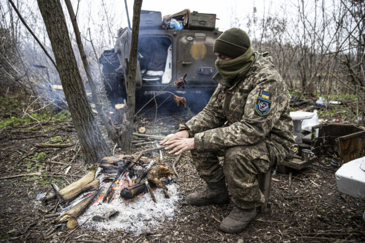 Ukrainian soldier sitting in front of a small fire