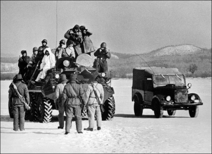 Chinese troops standing in front of a military vehicle overflowing with Soviet soldiers