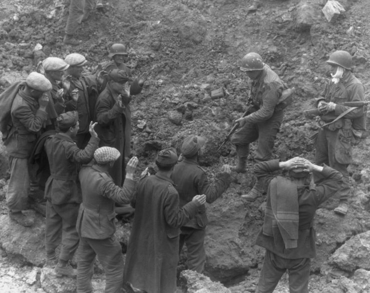 US soldier holding German troops and laborers at gunpoint on Omaha Beach