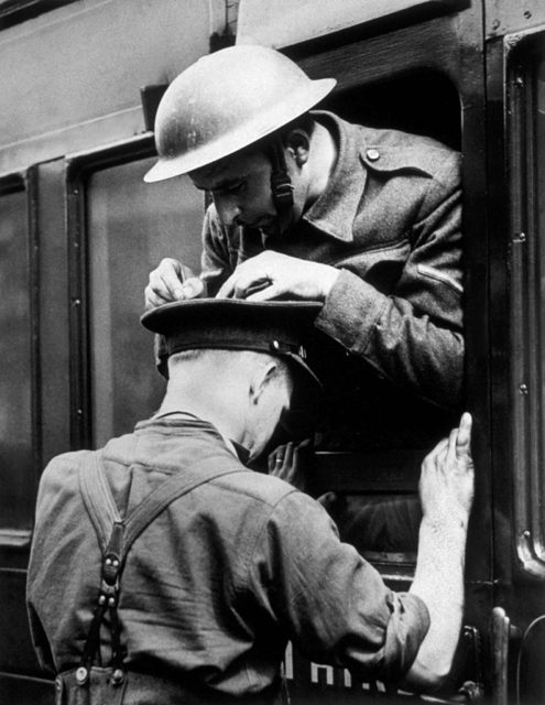 Soldier using a comrades head as a writing surface for a letter