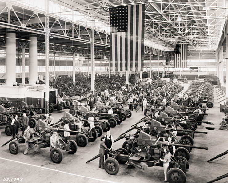 Workers standing among rows of Bofors anti-aircraft guns