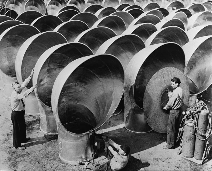 Shipbuilders standing among rows of cowls